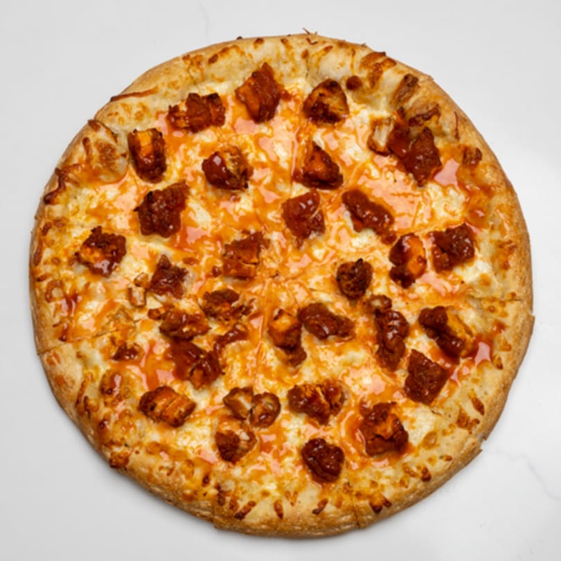 A whole Pizza Place pizza with a golden crust, melted cheese, and buffalo chicken pieces.